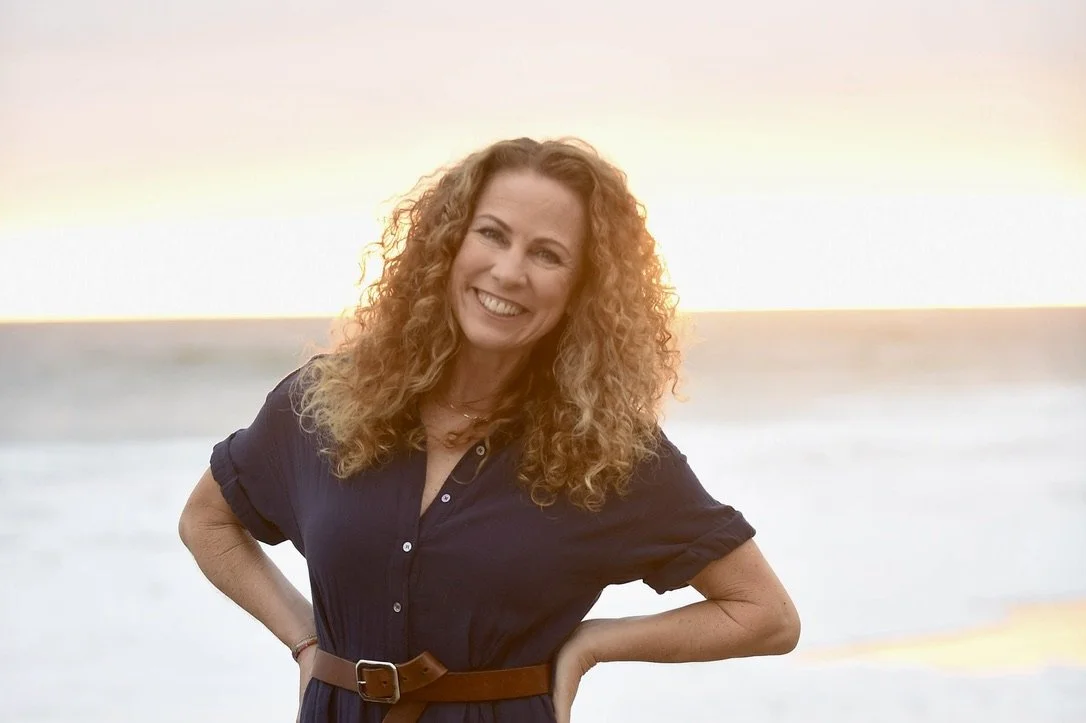 Parenting coach Jeanine Mouchawar smiling on the beach at sunset.