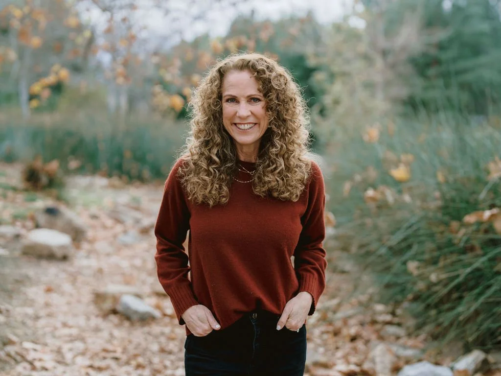 Parenting coach Jeanine Mouchawar standing on a wooded path, smiling with confidence