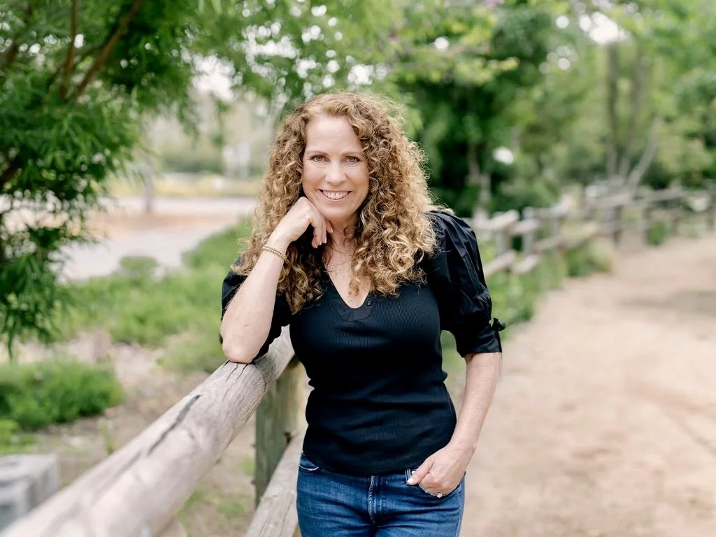 Jeanine Mouchawar, parenting coach for parents of teenagers, standing outdoors and smiling, offering guidance on calm communication and connection with teens.