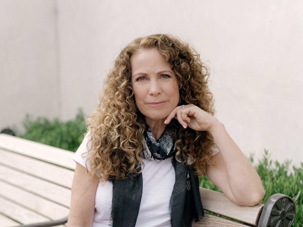 Parenting coach Jeanine Mouchawar sitting on a bench