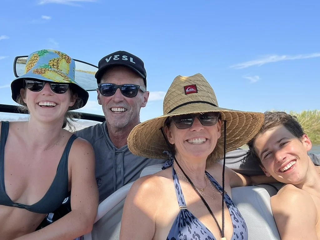 Jeanine Mouchawar smiling with her family on a boat during summer, illustrating the importance of enjoying time together before the busy back-to-school season.