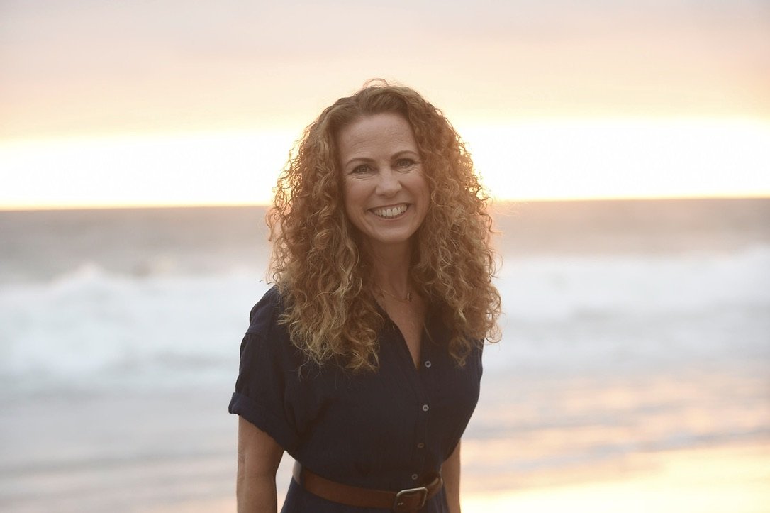 Jeanine Mouchawar smiling on the beach at sunset, reflecting on why everyday parenting reminders feel so emotionally exhausting.