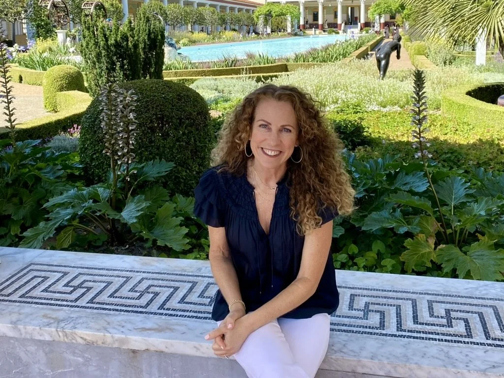 Jeanine Mouchawar smiling outdoors in a peaceful garden, representing calm, connected parenting during the stressful back-to-school season.