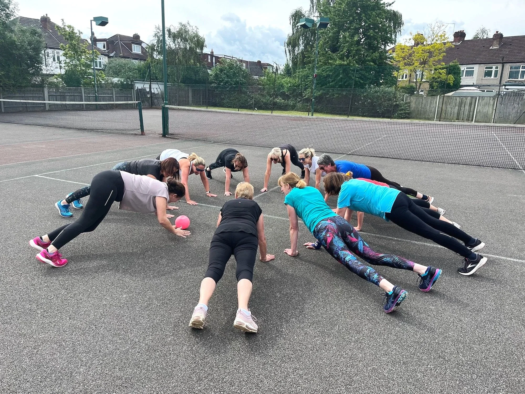 Ladies doing exercise outdoors on a tennis court