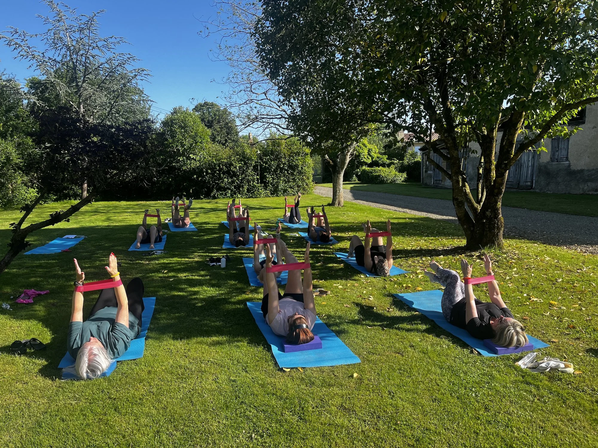 Ladies practicing Pilates on the grass on Pilates mats outdoors in the sun of South West France.