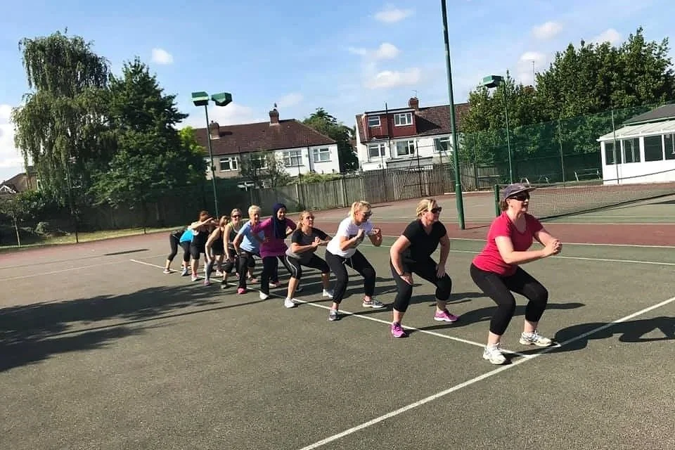 Fitness classes in a tennis court outside in Raynes Park