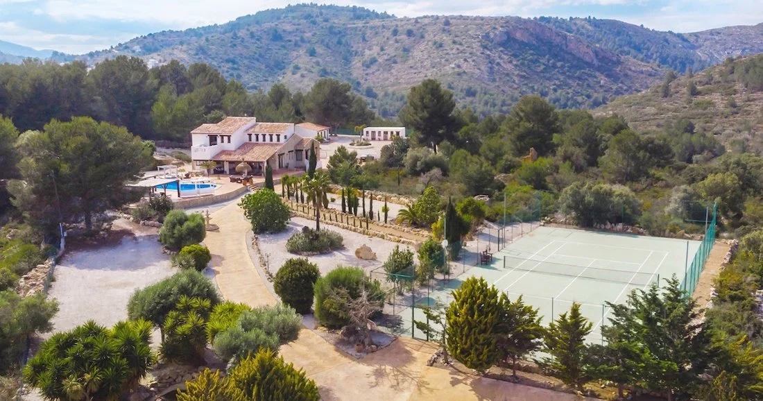 View of Spanish Pilates retreat with tennis courts, pool and mountains