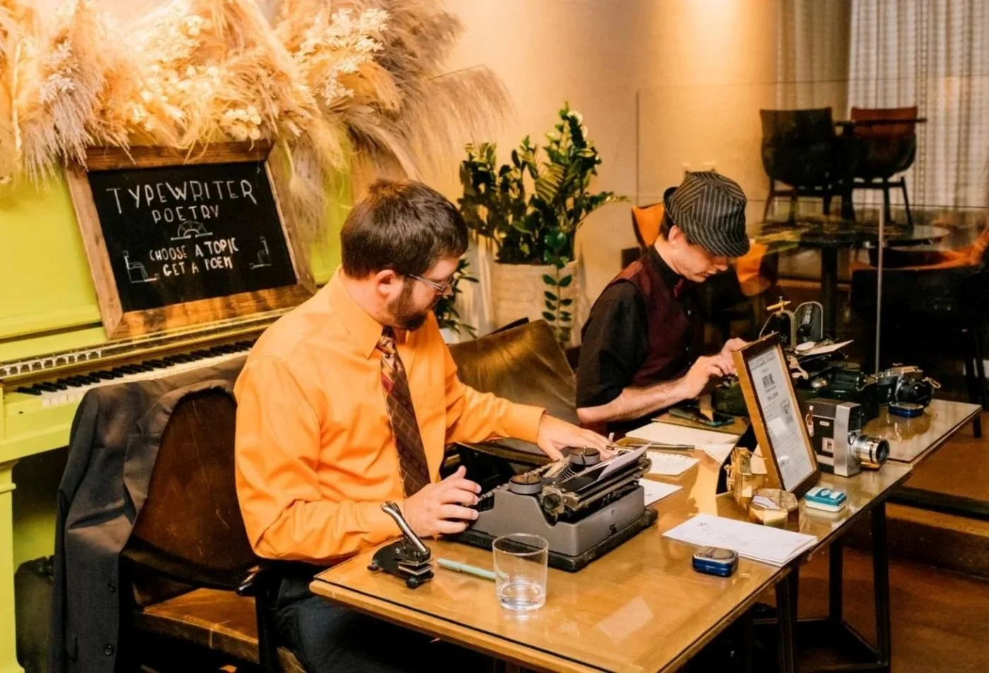 With Ink Typewriter Poets Mark Petersen and Joseph Jablonski writing live poetry at a wedding in a photo by Mason Photography.