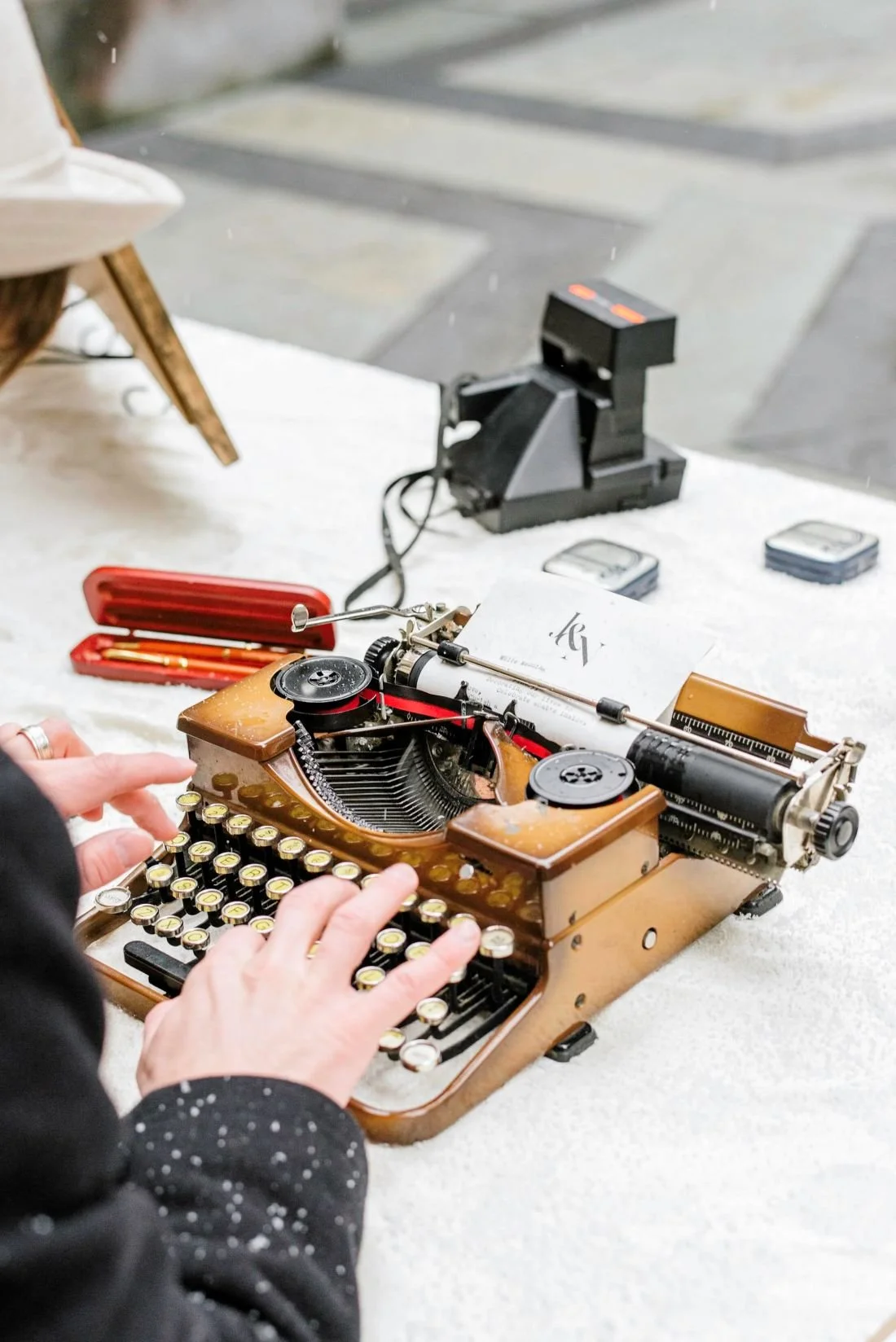Mark Petersen's teal Royal typewriter for poems on a desk outside at a wedding in a photo by Stephanie Dee Photography.