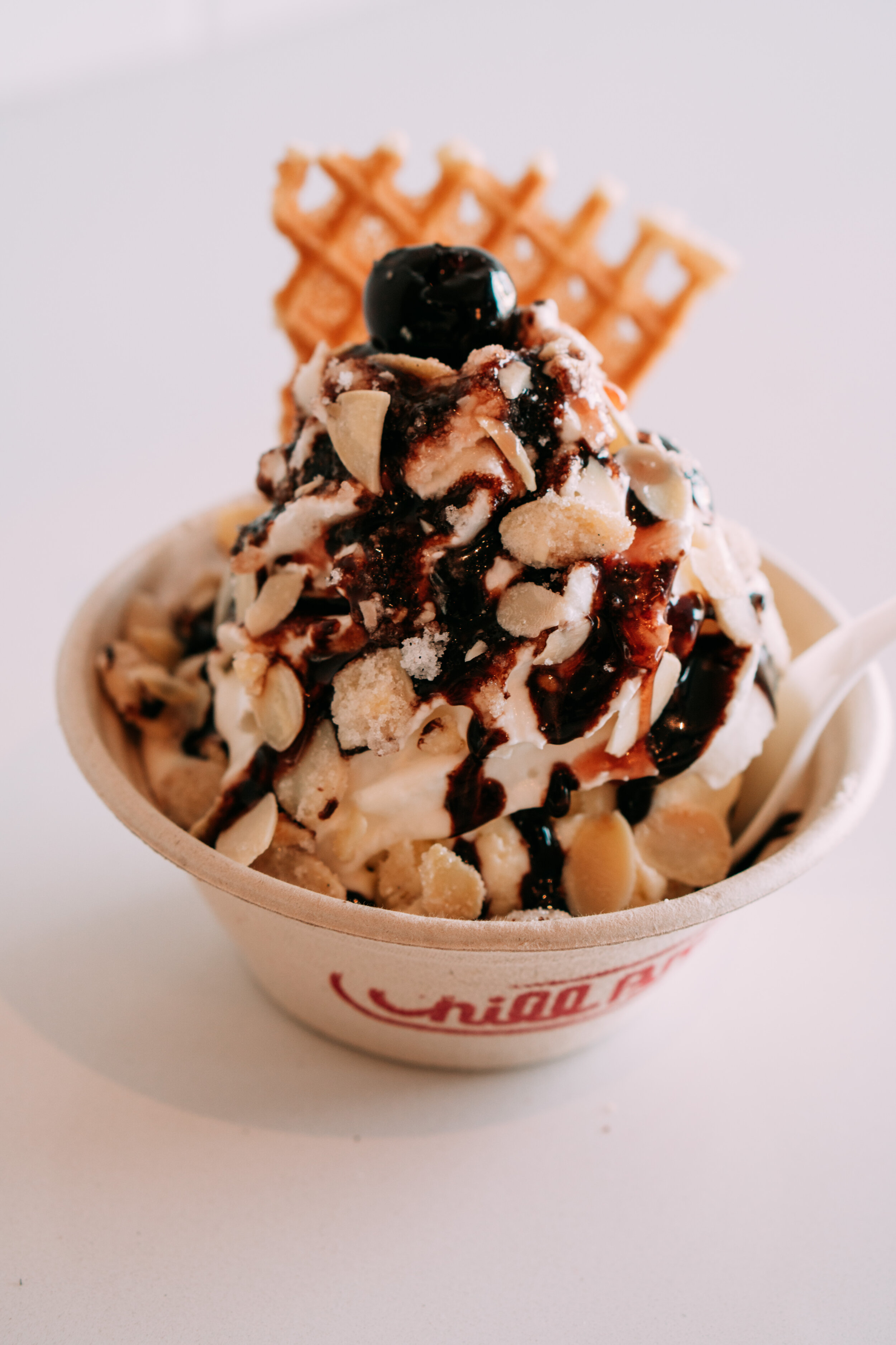 a single scoop sunday with hot fudge, whipped cream, candied almonds and a cherry on top 