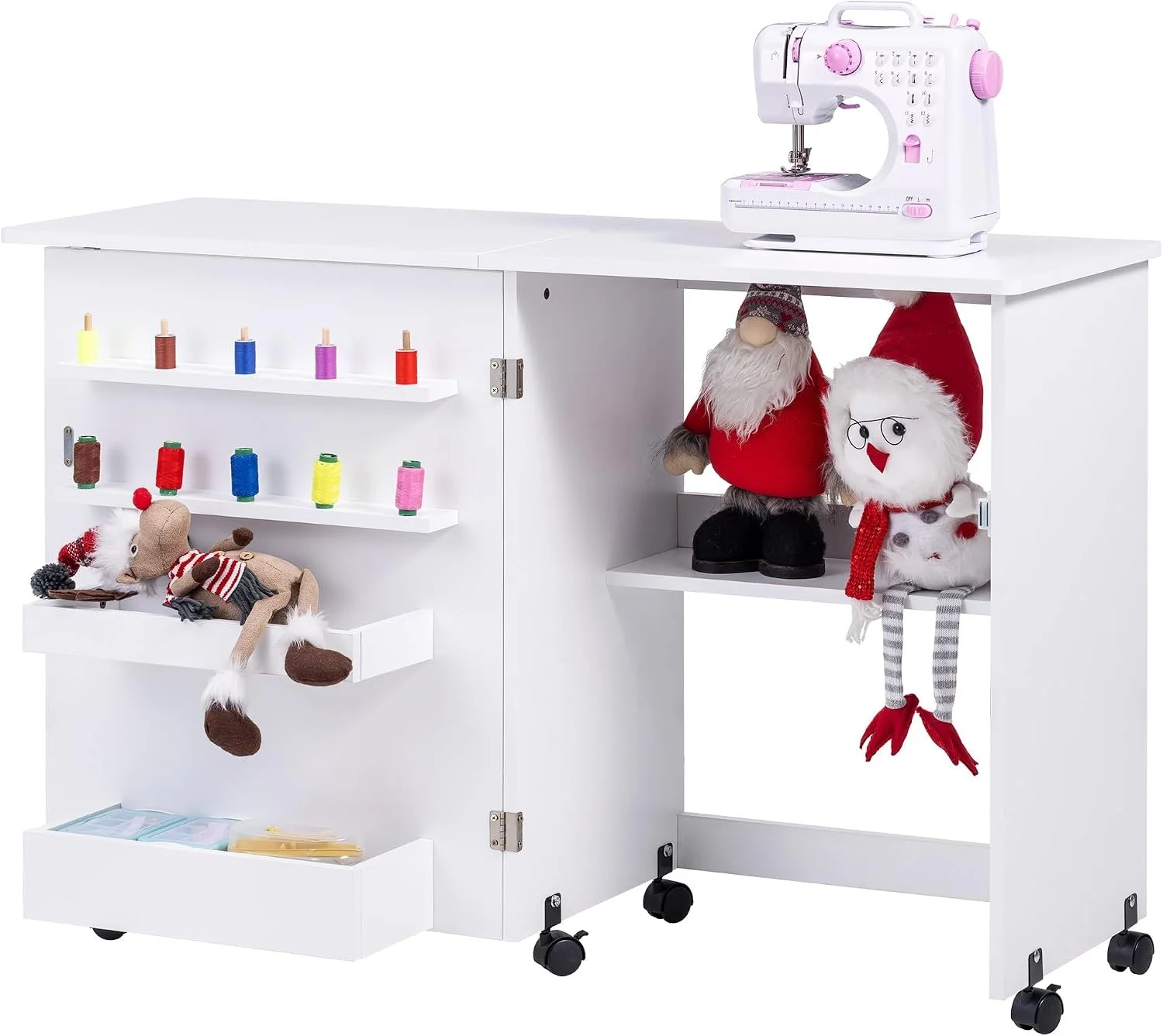 White sewing cabinet with a pink and white sewing machine on top, decorated with Christmas plush toys including Santa Claus and a snowman, as well as small spools of thread in various colors and a reindeer plush toy.