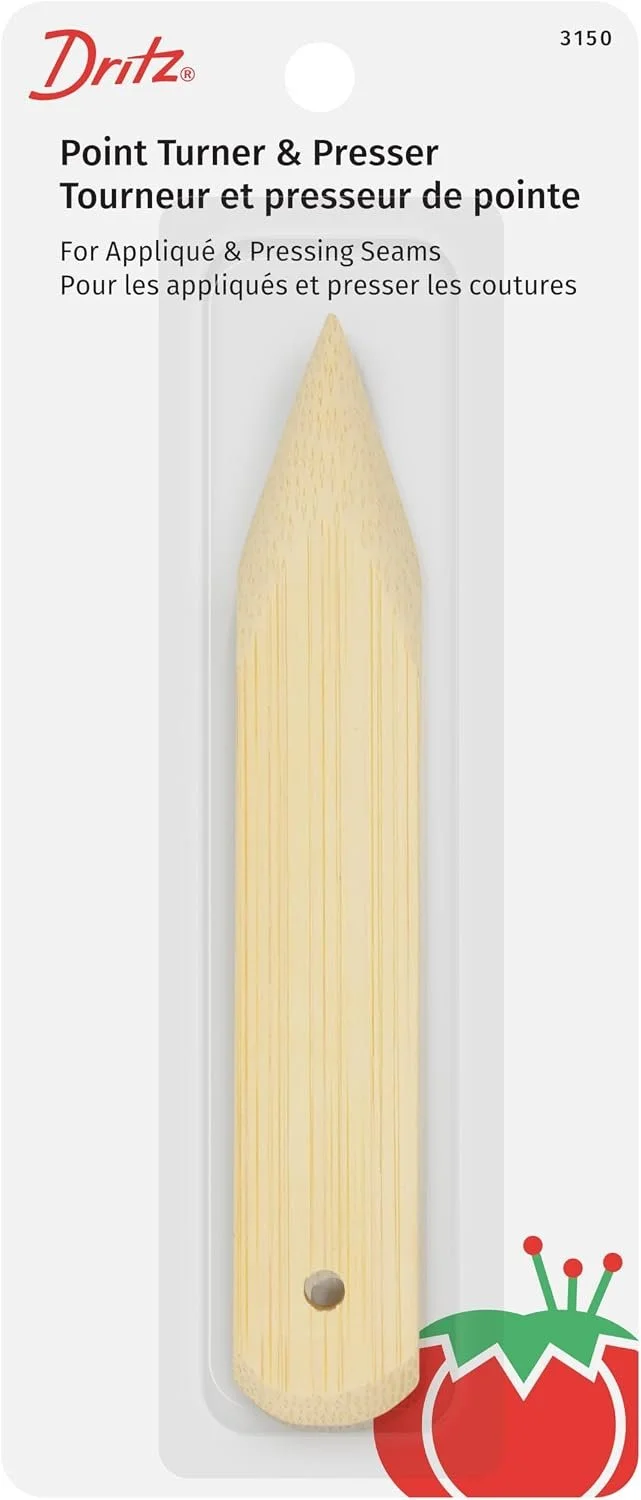 A point turner and presser tool in light wood with a pointed end, displayed on packaging with text in English and French, brand name Dritz, with a tomato graphic on the bottom right corner.