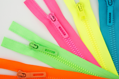 Close-up of colorful zippers in pink, green, yellow, blue, and orange on fabric