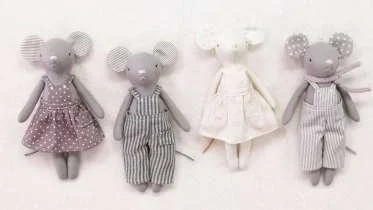 Four mouse-shaped plush toys dressed in different outfits, including dresses and striped overalls, lined up against a white background.