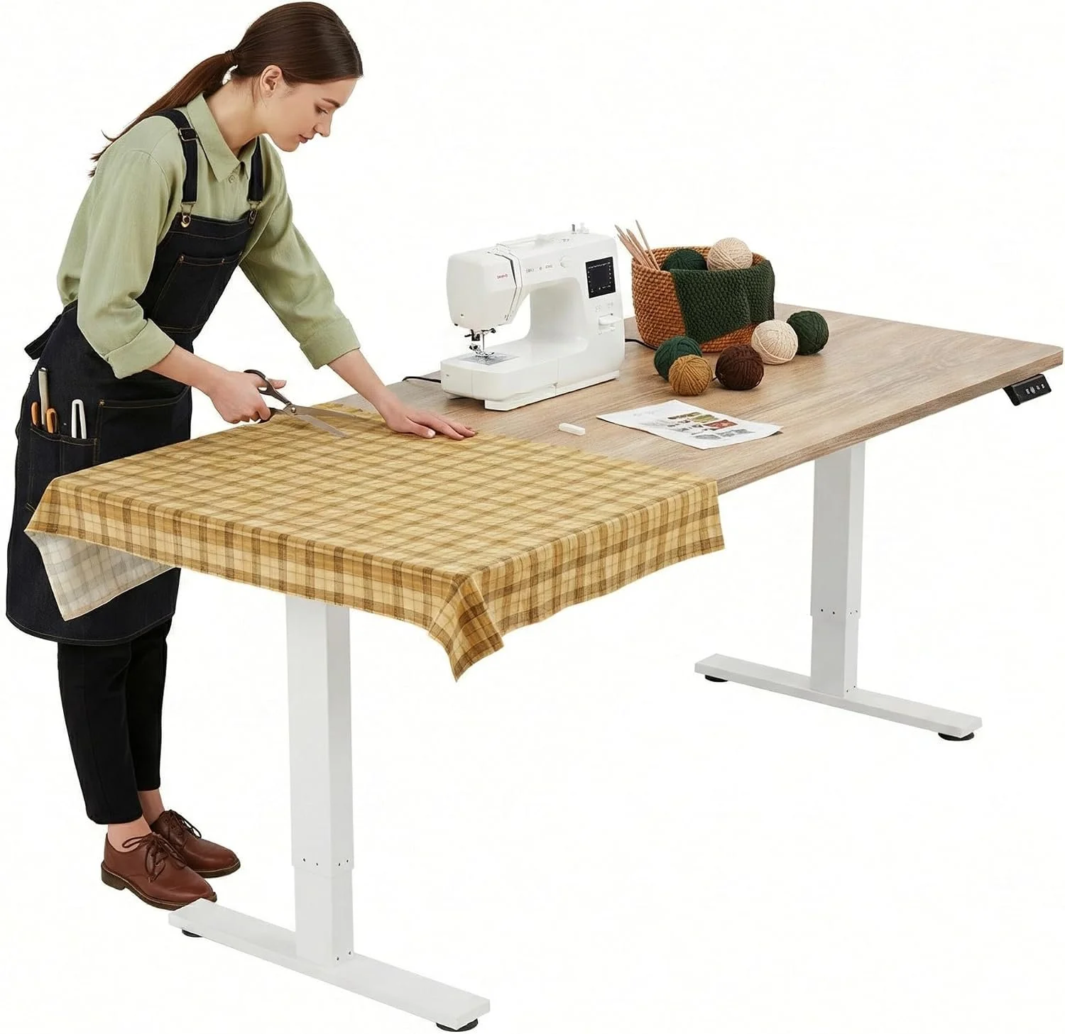 A woman with a ponytail, wearing a beige shirt and black apron, cutting fabric on a table with a scissors. The table has a checkered tablecloth. On the right side of the table, there is a sewing machine, a basket with yarn balls, and knitting needles.