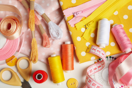 Sewing supplies including threads, scissors, measuring tape, and fabrics in bright colors