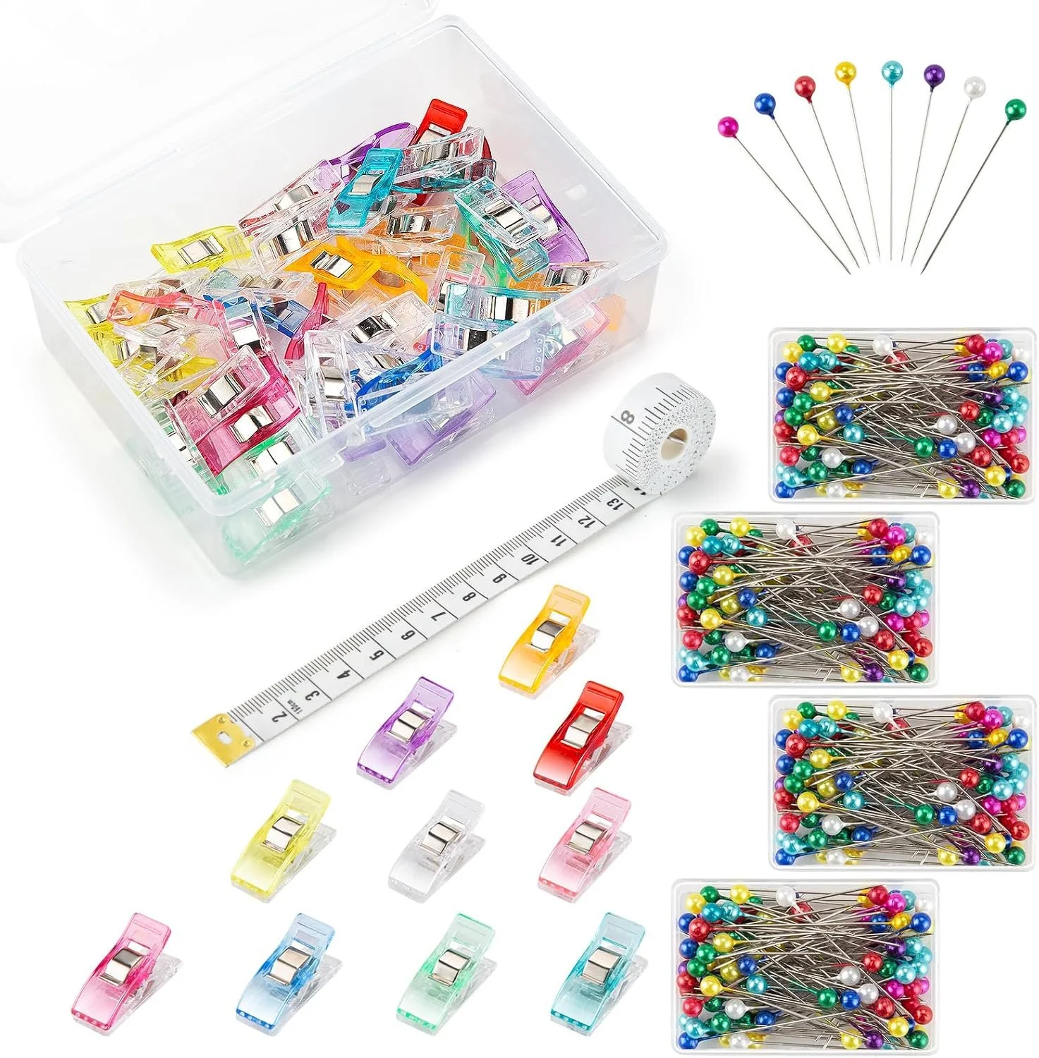 Colorful assorted paper clips, straight pins with multicolored round heads, a measuring tape, and a clear plastic storage box.