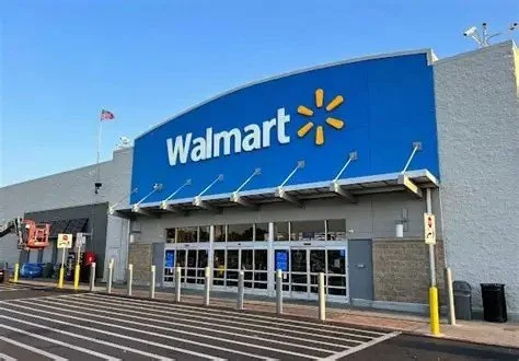 Exterior of a Walmart store with a large blue sign and entrance doors in the foreground.