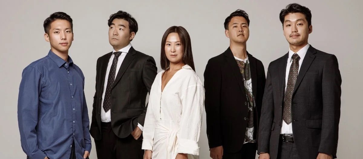 Group of five professionally dressed Asian individuals standing in a row against a plain background