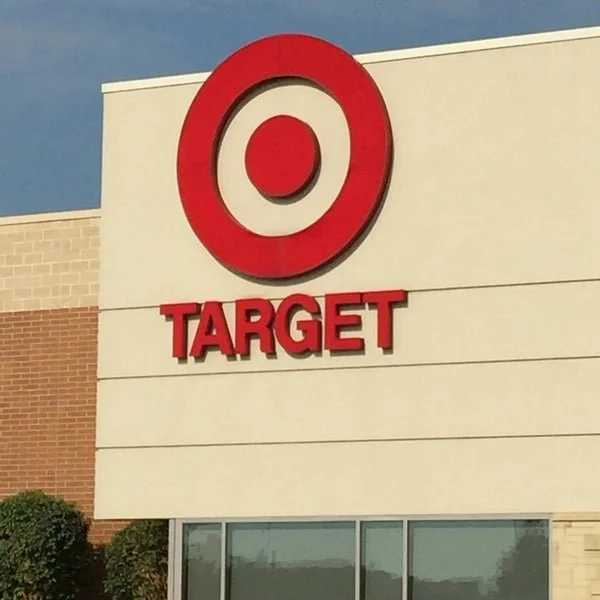 Target store sign with red bullseye logo and red 'TARGET' text on a beige wall.