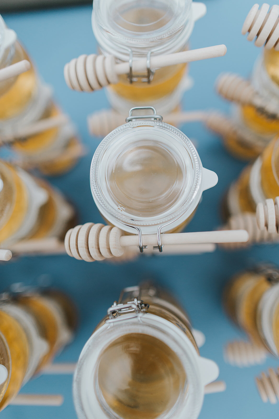 honey in glass jars with honey dipper in rows for wedding guests