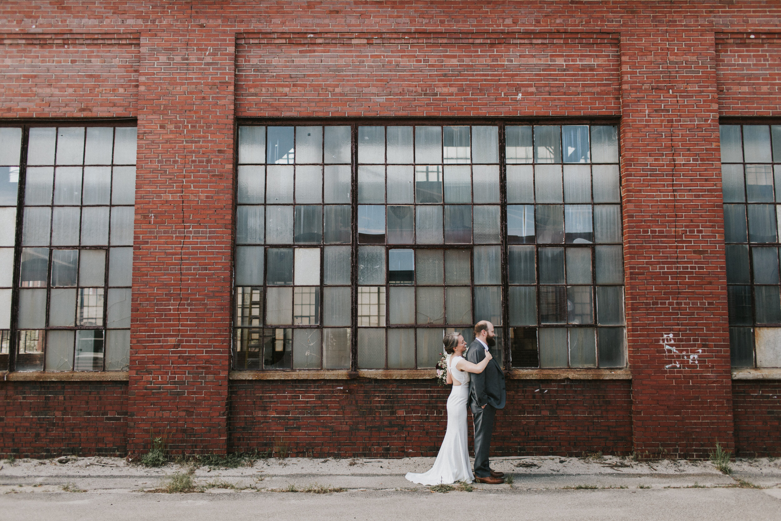 bride and groom first look in front of brick building with tall glass windows