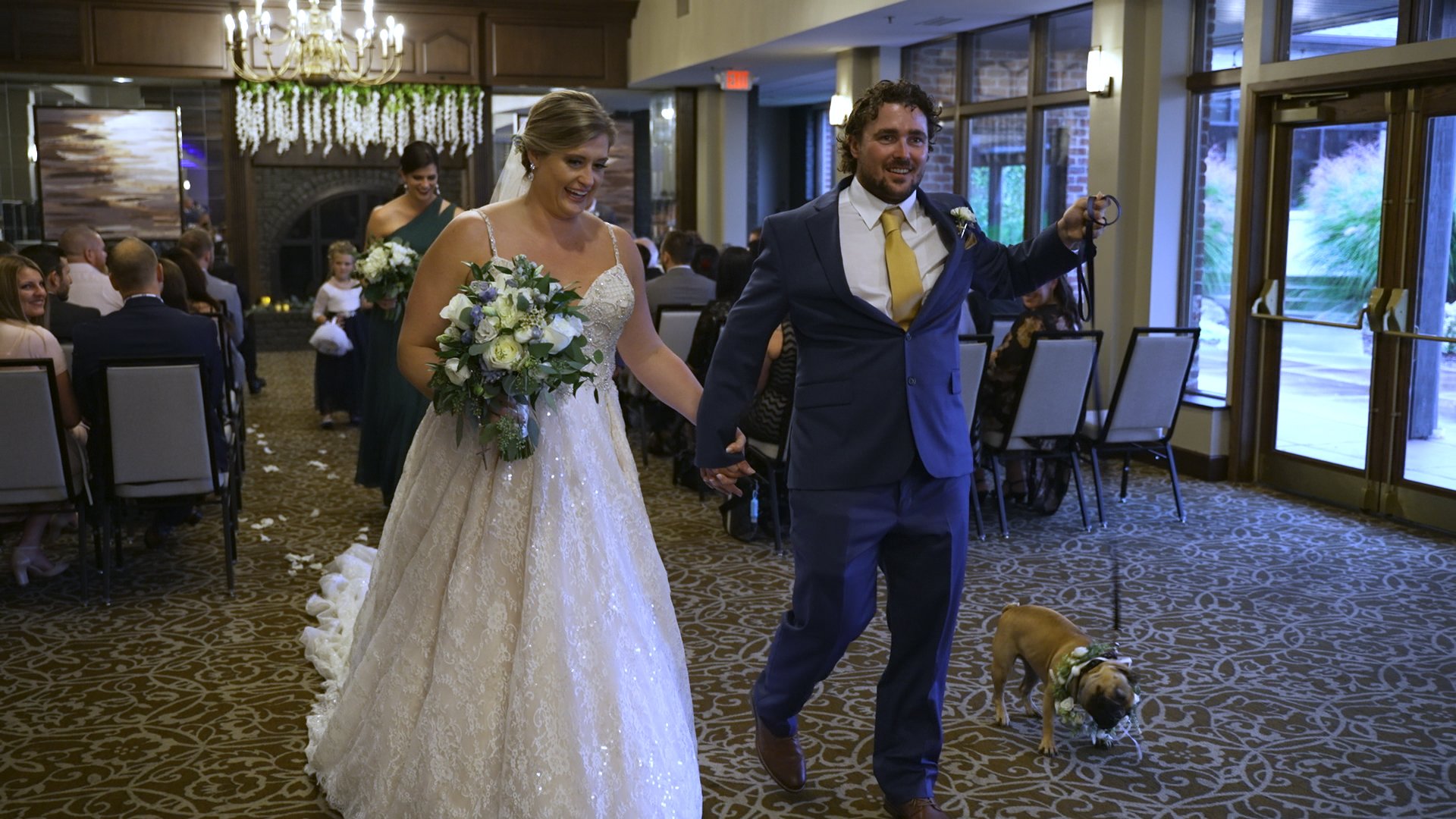 Bride and groom walking down the aisle with their french Bulldog
