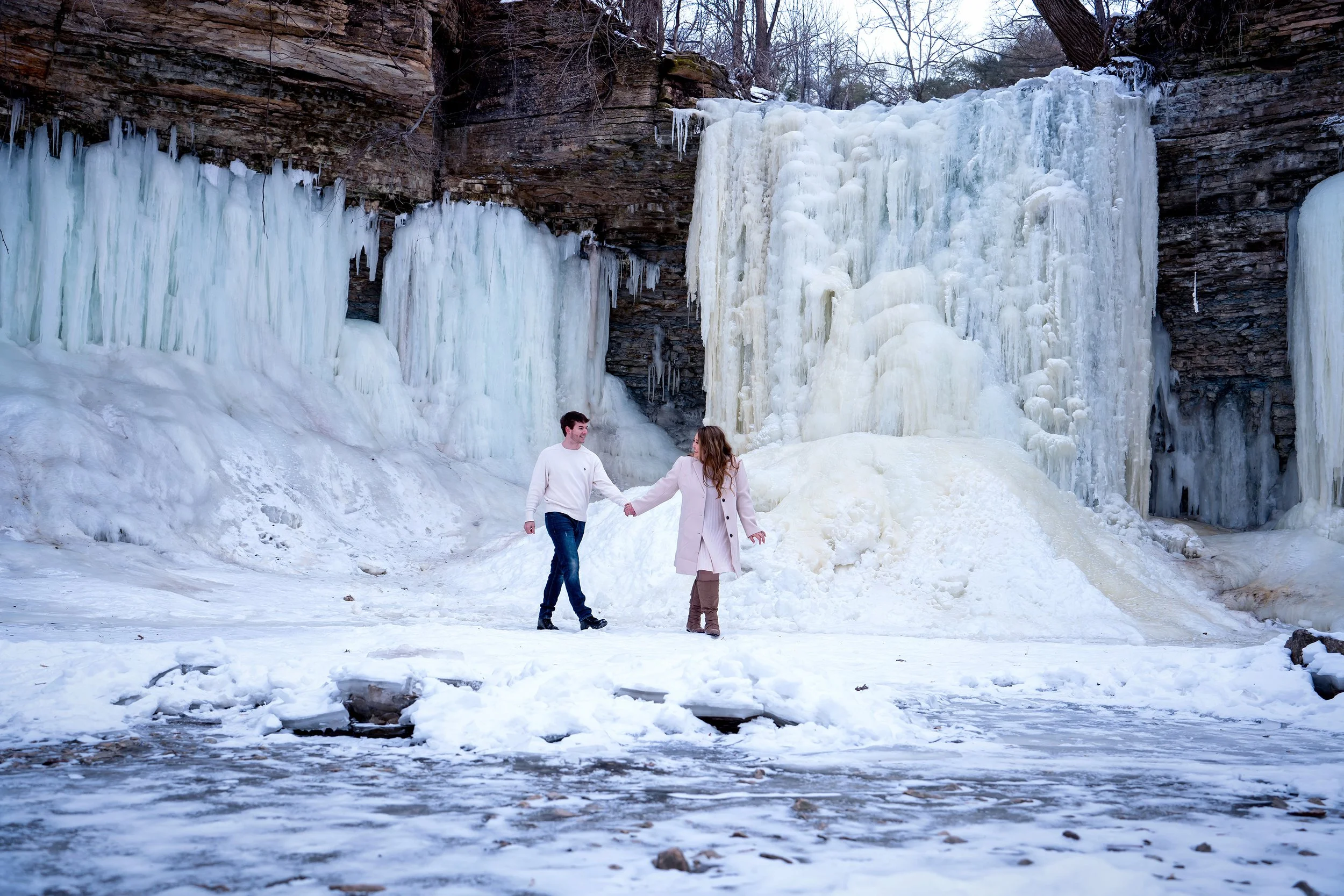 Wisconsin Bride leading a groom through snowy path at Wequiock Falls | winter engagement photos by AA Studios LLC