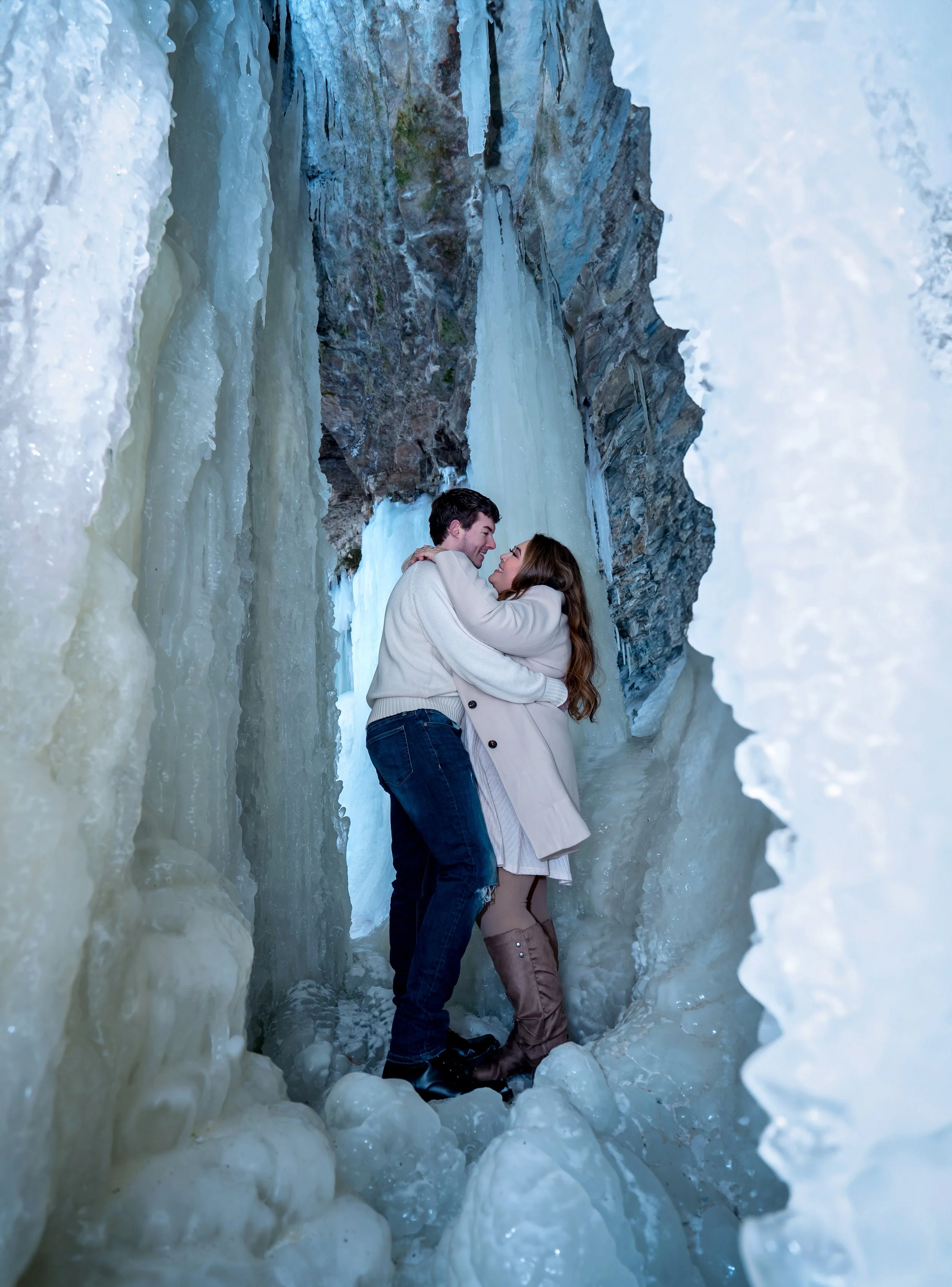 Couple inside icy tunnel behind frozen waterfall at Wequiock Falls Wisconsin