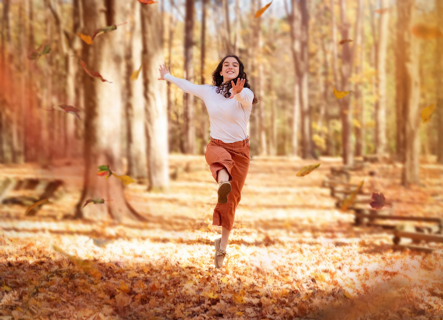 Highschool senior jumping in the golden fall leaves