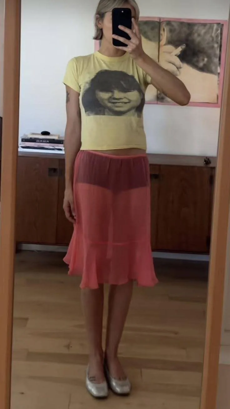 mirror selfie woman showing red sheer skirt and yellow t shirt