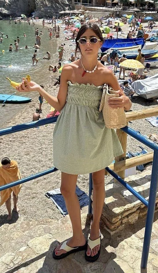 woman in a strapless green sundress at popular beach in europe