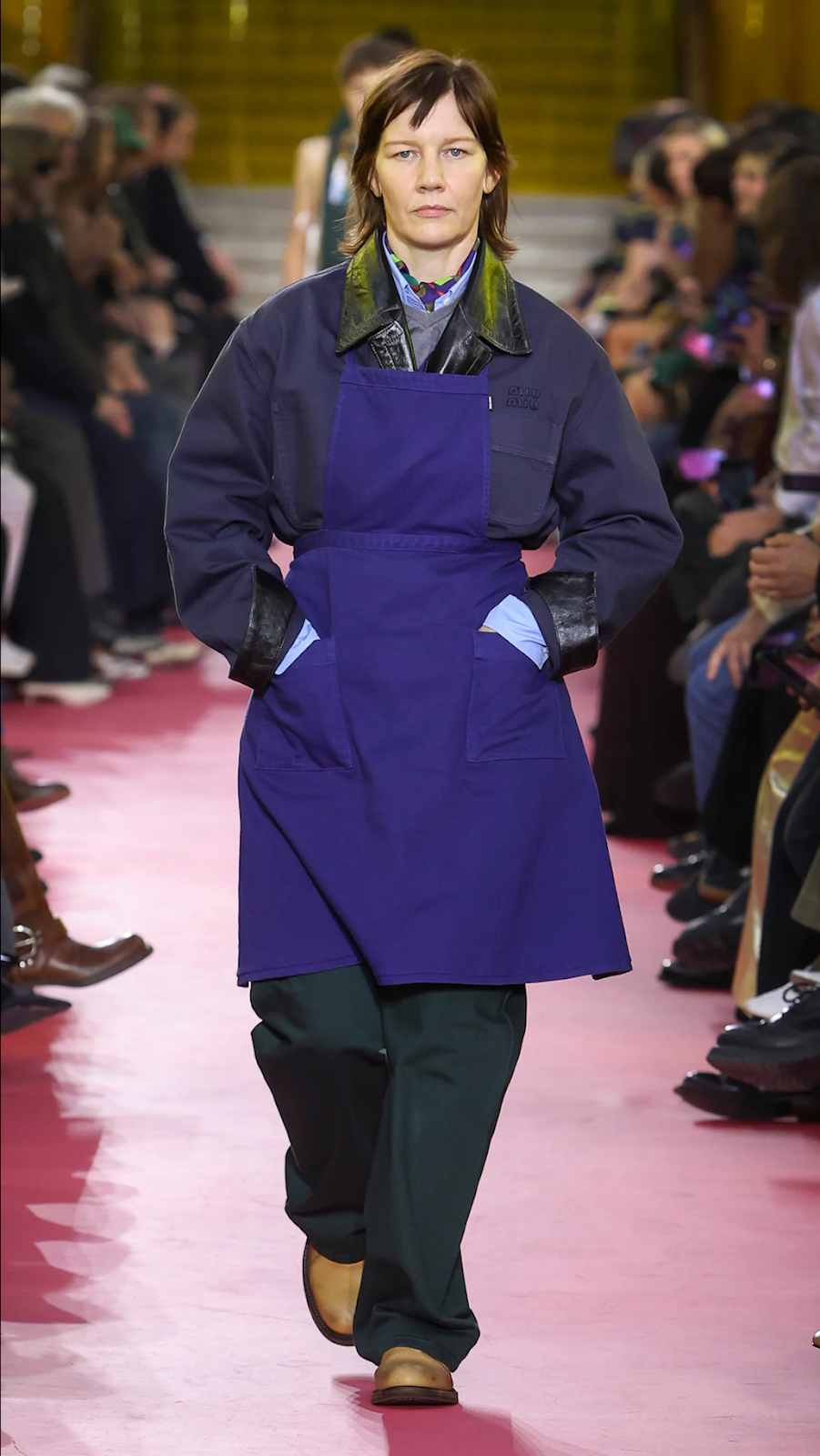Model wearing a colorful blue oversized apron on the runway