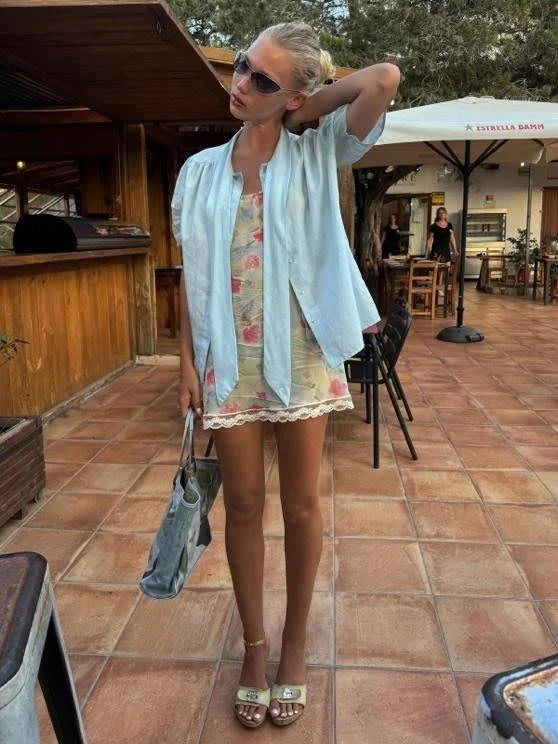 woman in sundress wearing sunglasses and light blue button down shirt