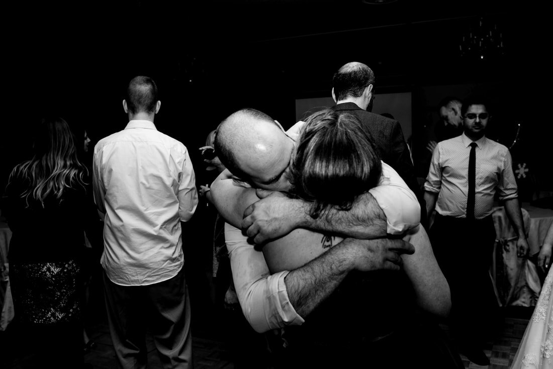 Black and white picture of couple hugging each other dancing in the wedding party.