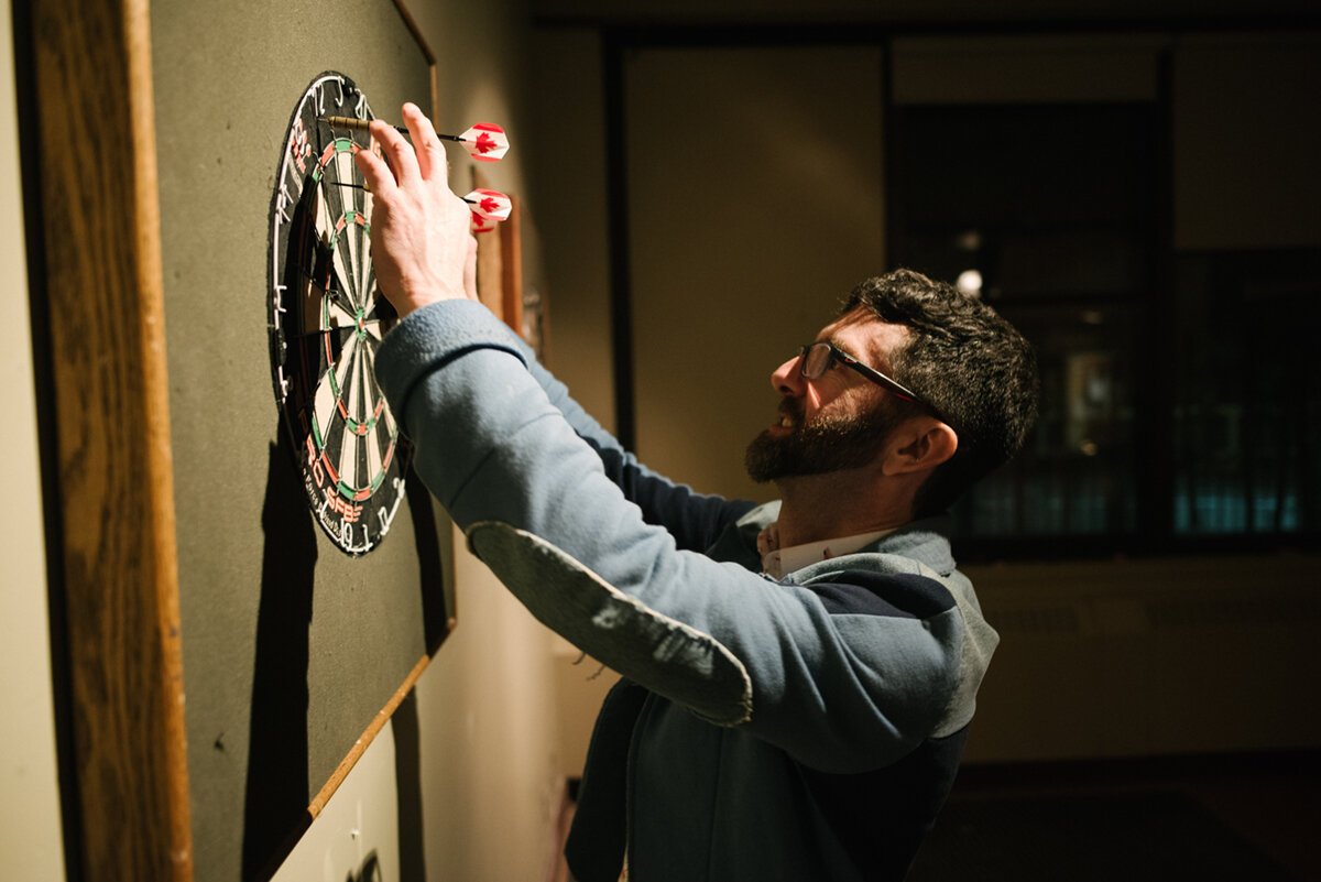 Guest removing the darts from the board at wedding reception in Kingston, Ontario