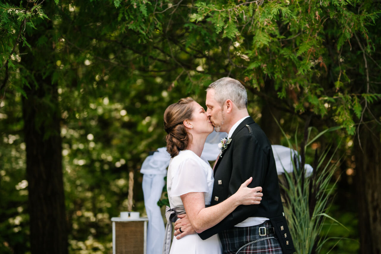 Bride and groom sharing their first kiss during their ceremony in Ottawa
