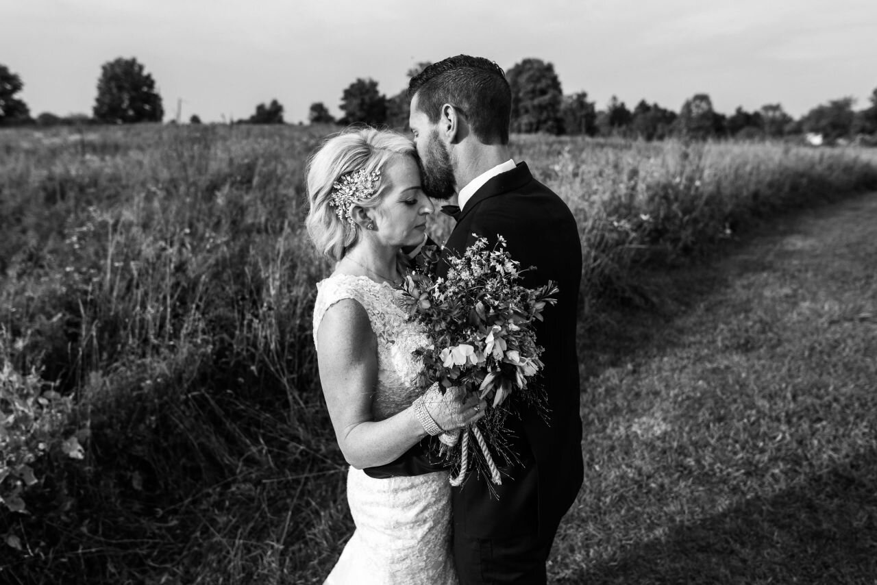 Bride and groom embracing in field at rural Ontario elopement 