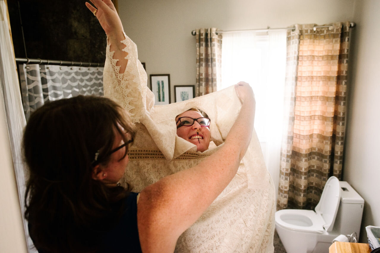 Friend helping the bride get dressed for rural elopement near Kingston, Ontario