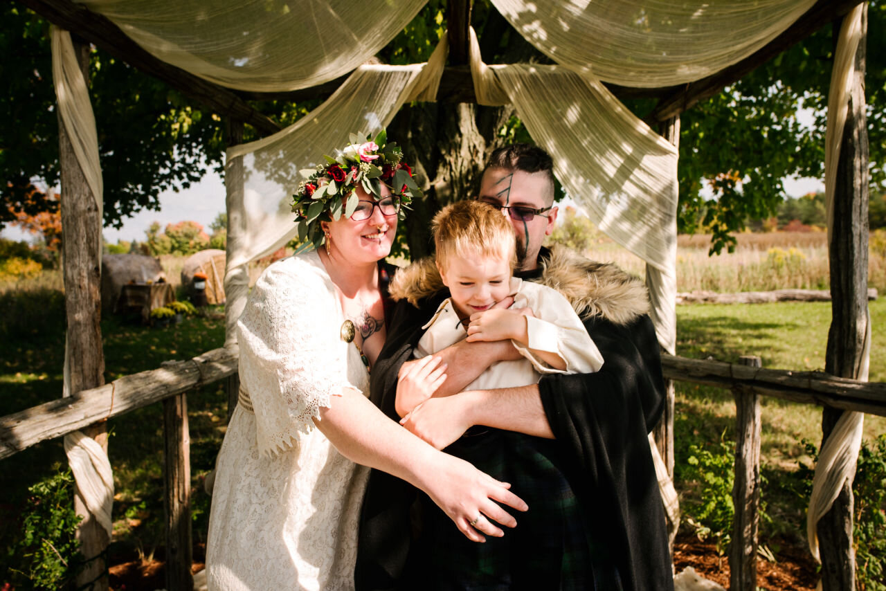 Bride, groom, and son, under wedding tent at rural elopement near Kingston Ontario