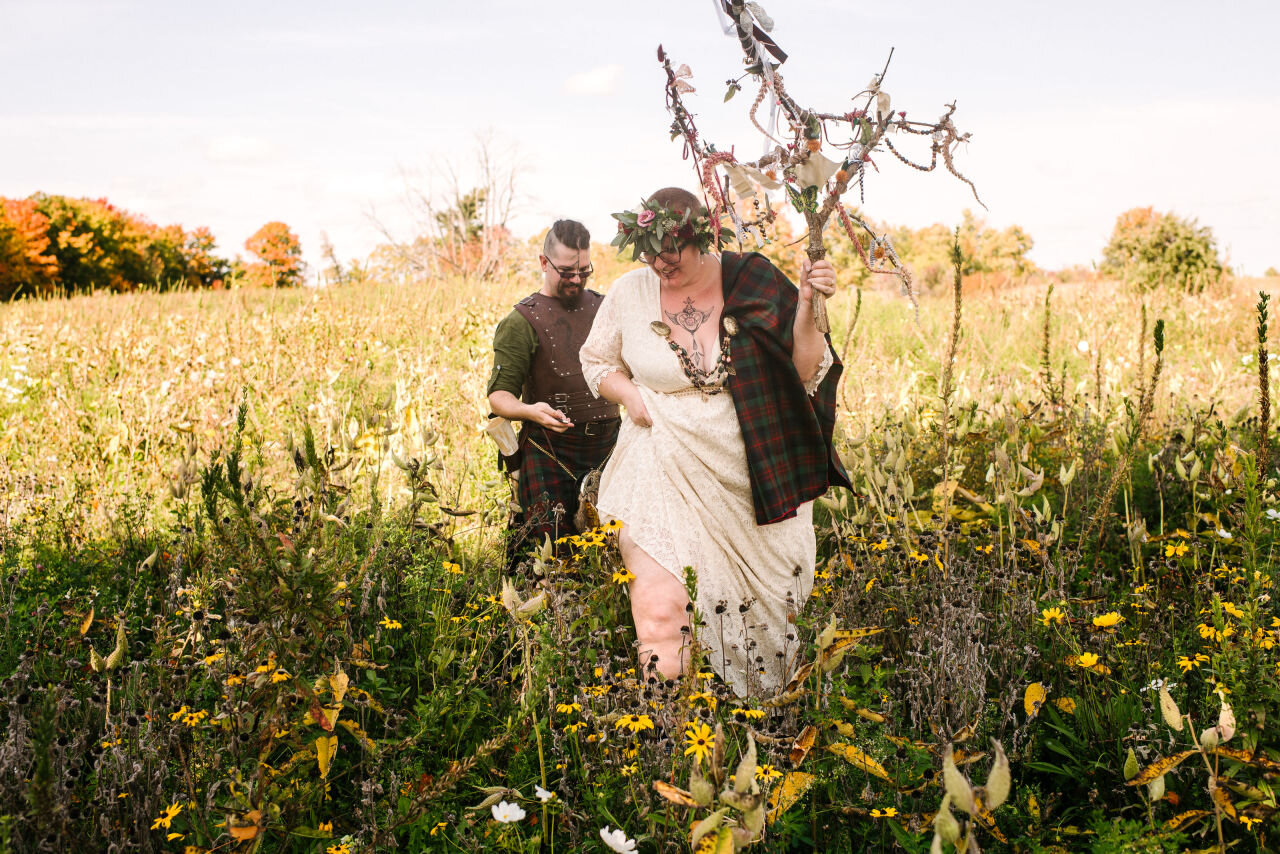Bride and groom walking through wildflowers at their rural elopement near Kingston, Ontario