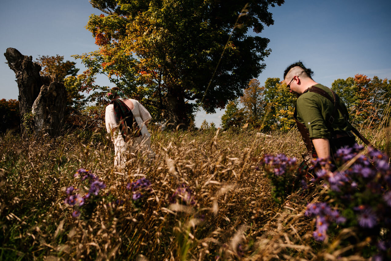 Bride and groom moving through fall foliage during rural elopement near Kingston, Ontario