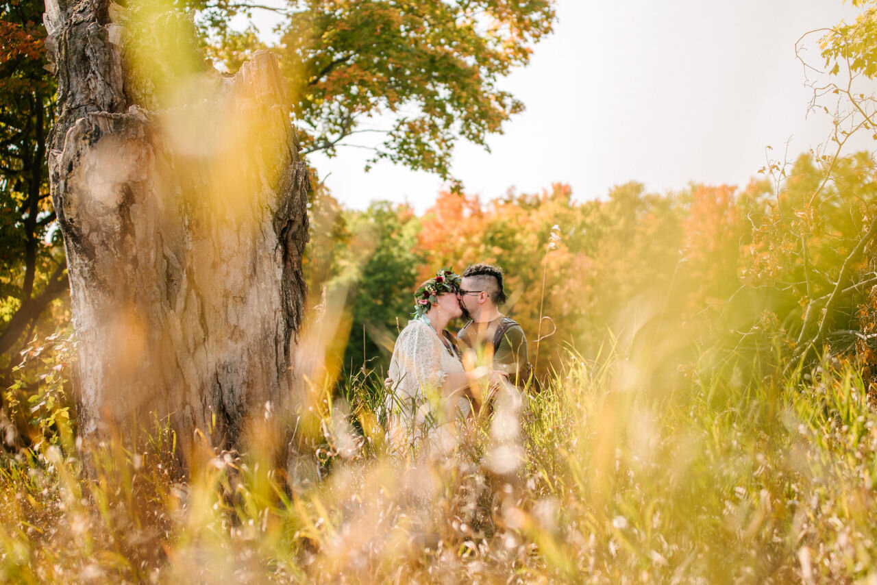 Bride and groom kissing among fall foliage at rural elopement near Kingston, Ontario