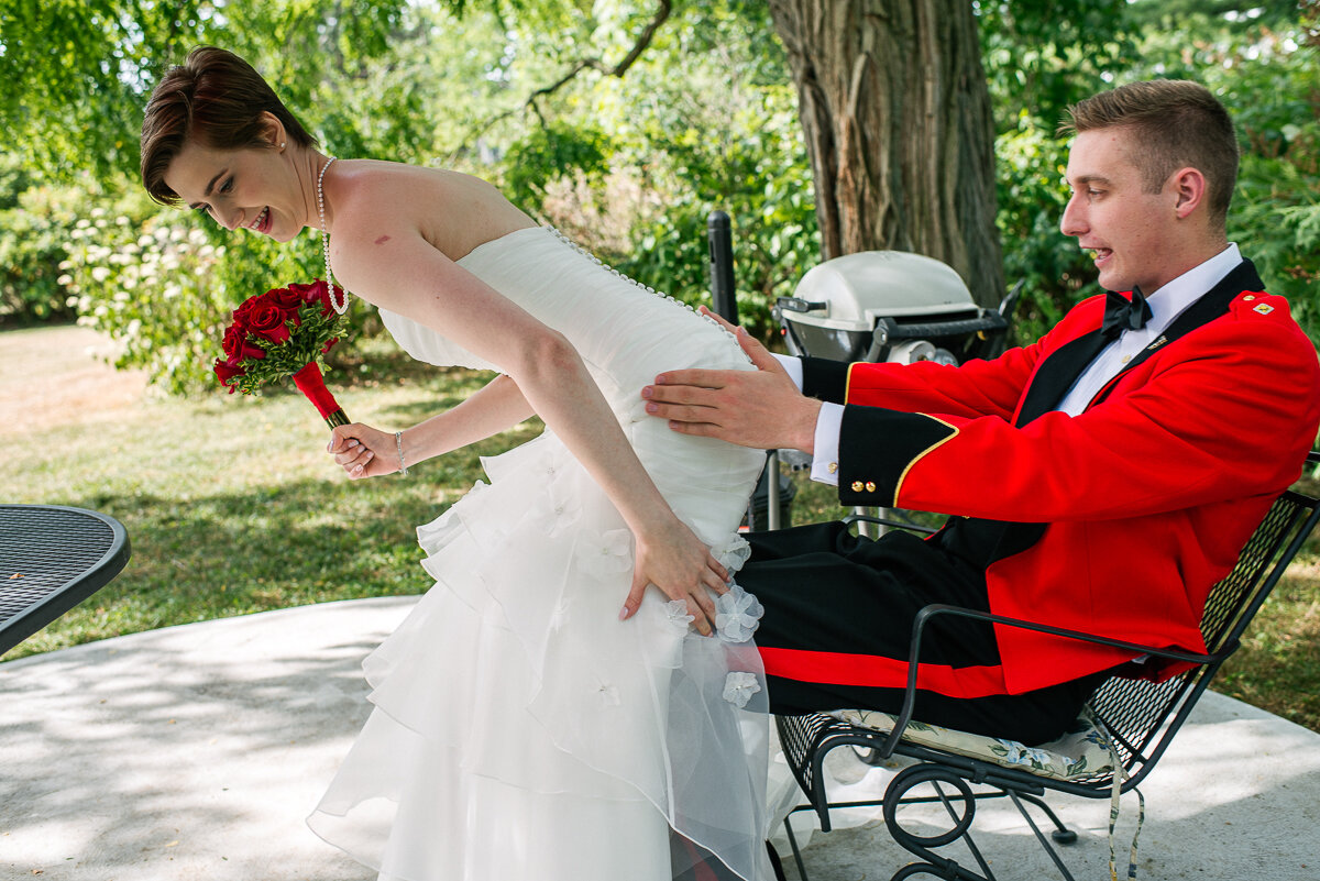 Bride trying to sit on the groom's lap on a park bench