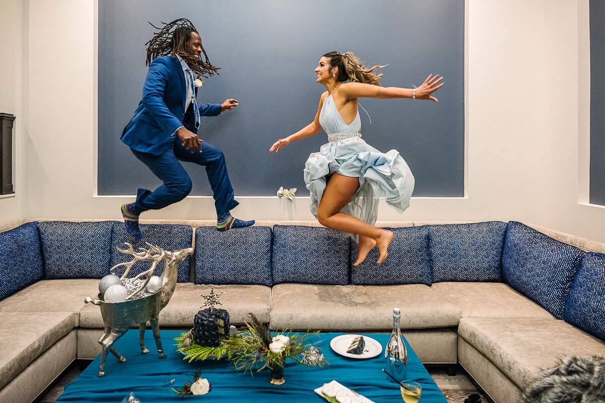 Bride and Groom jumping on couch after having dessert 