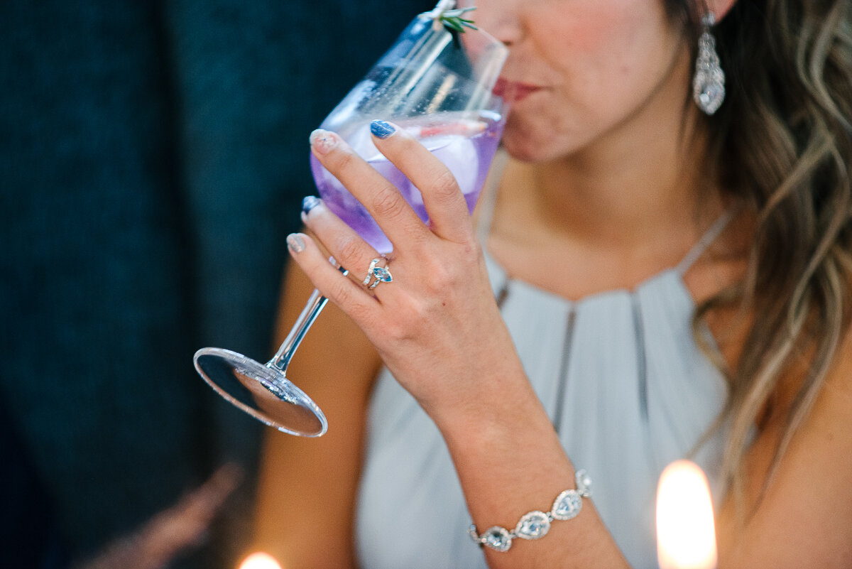 up close photo of bride holding purple mixed drink from Frontanc Club and wedding jewellery 