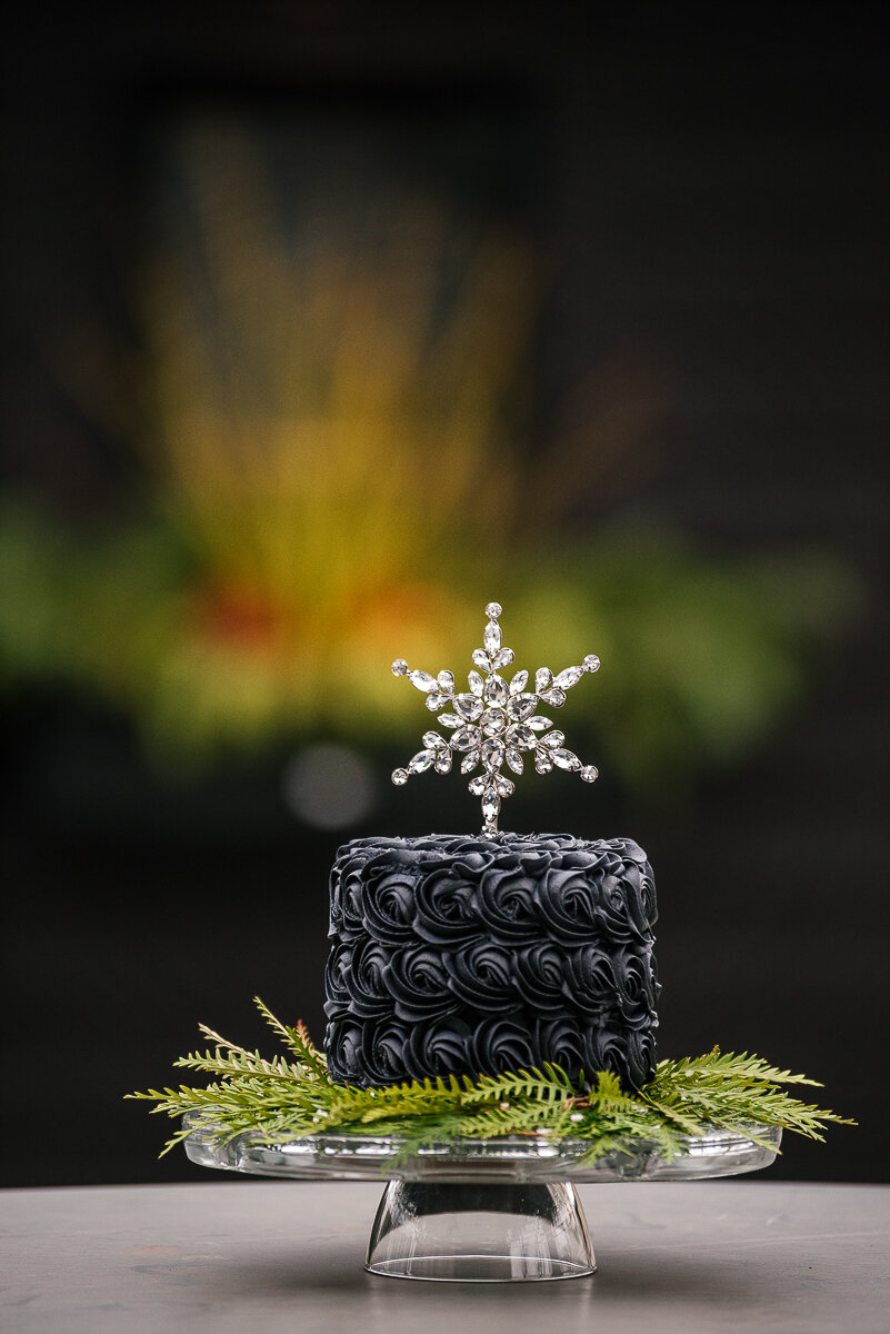 black buttercream cake with crystal snowflake placed on top for decoration 