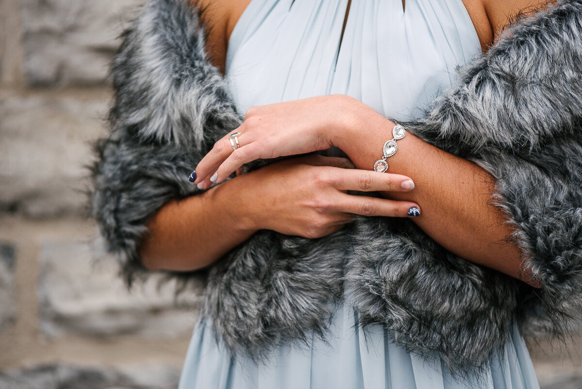 Bride wrapped in fur scarf, showing winter nail art and ring 