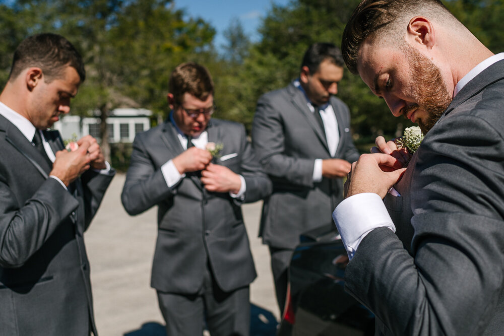 groomsmen putting on their boutonnieres for the wedding ceremony 