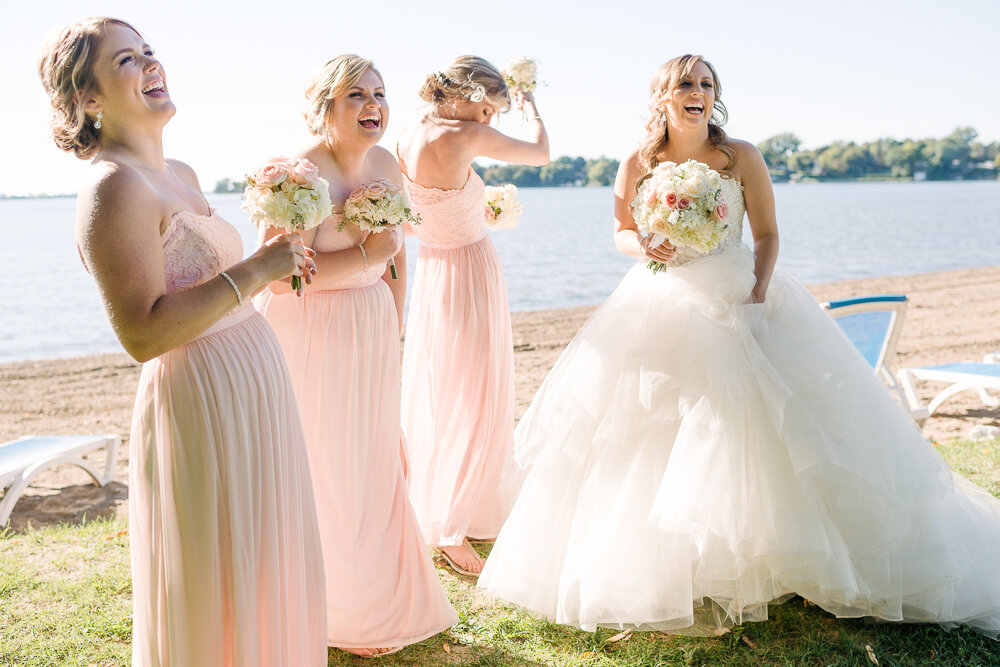 bride and bridesmaids laughing together on beach 